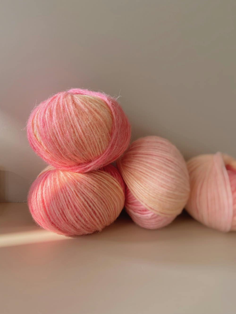 A pile of blush and cream pink yarn skeins in soft light